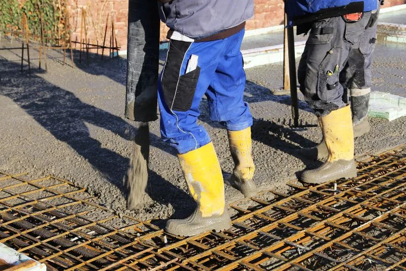 two workers pouring concrete mix